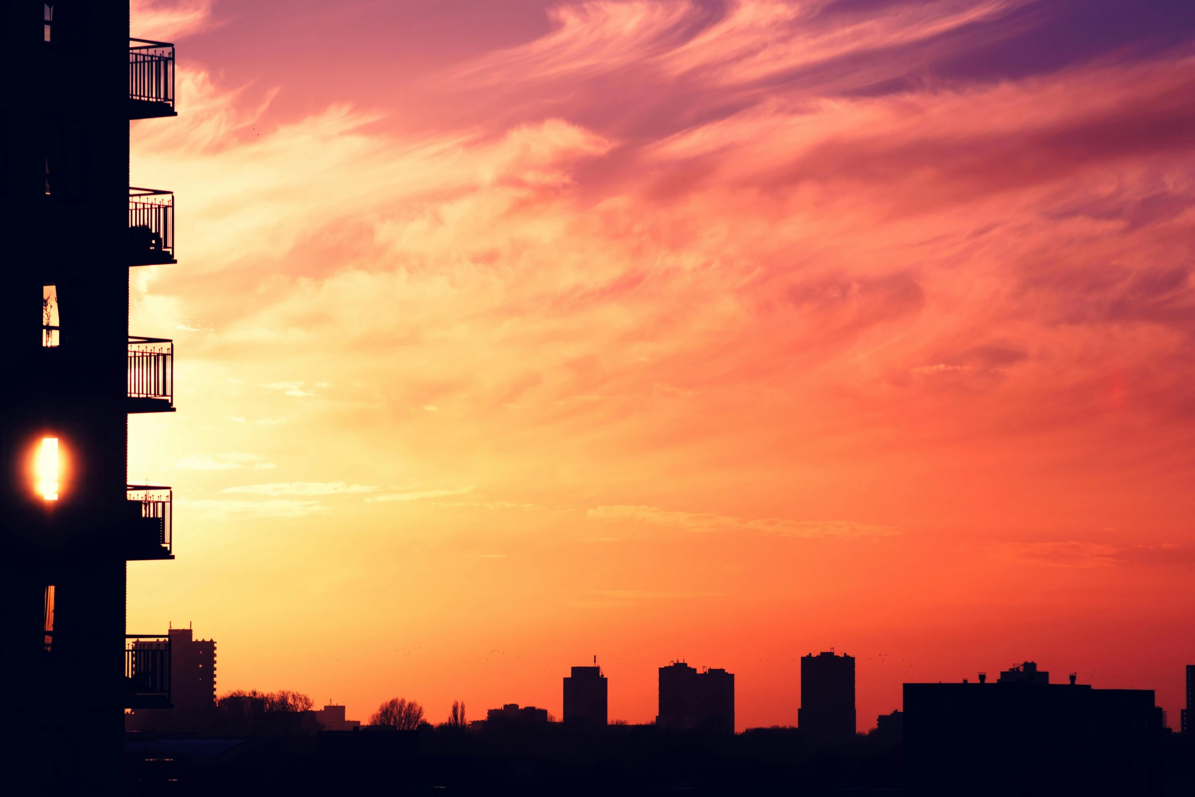 a tall building sitting in the middle of a city, pexels contest winner, romanticism, orange and red sky, violet and yellow sunset, skyline, from wheaton illinois