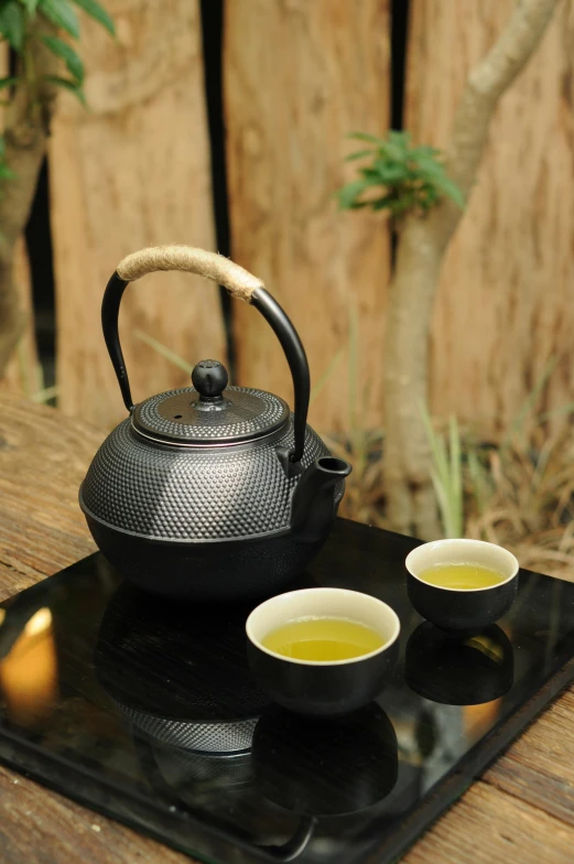 a tea pot and two cups on a tray, inspired by Sesshū Tōyō, unsplash, square, outdoor, large black kettle on hearth, green