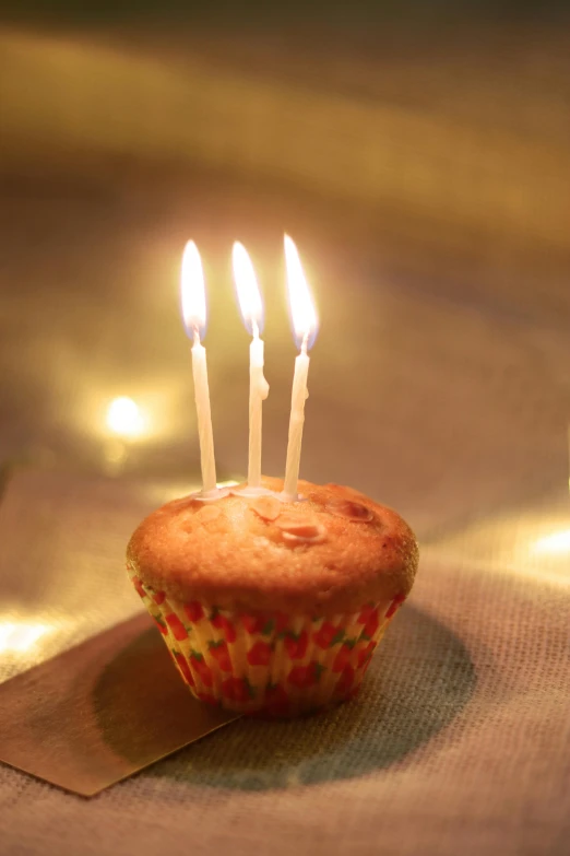 a muffin with three candles on top of it, pexels, happening, majestic light, years old, with a long, small