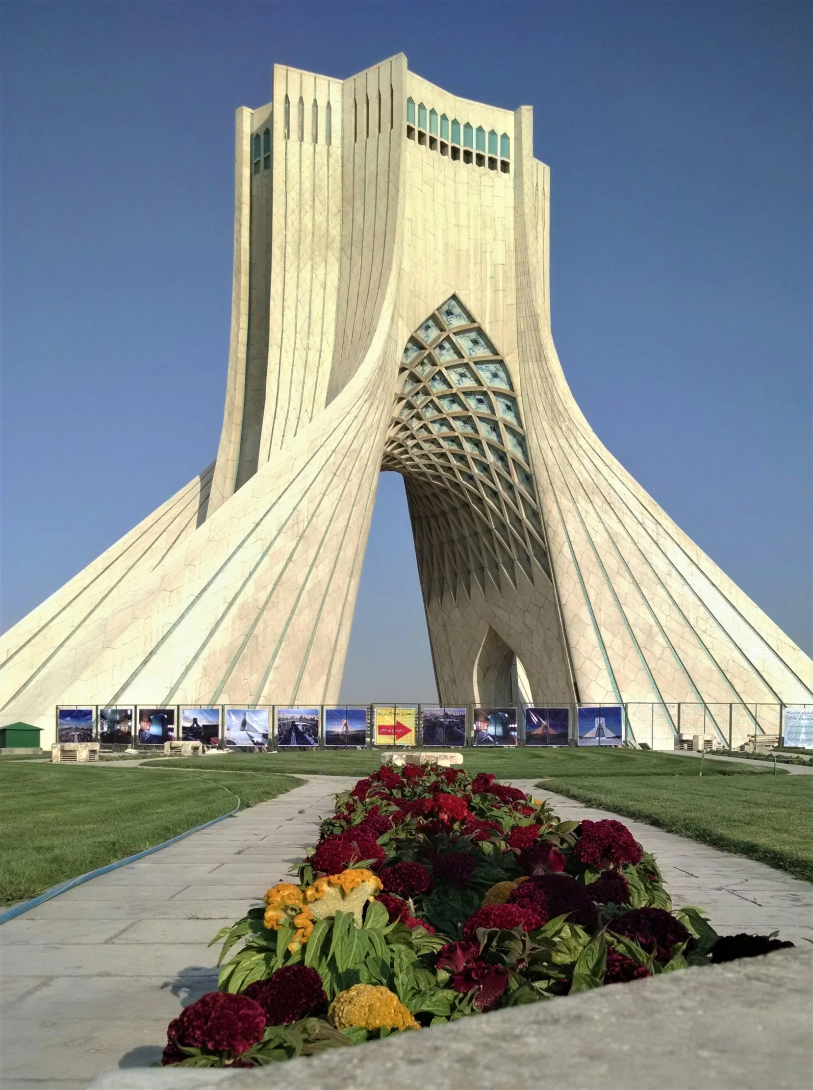 a very tall building with a bunch of flowers in front of it, a marble sculpture, inspired by Taravat Jalali Farahani, massive arch, nasa photo, khamenei, ( ( theatrical ) )