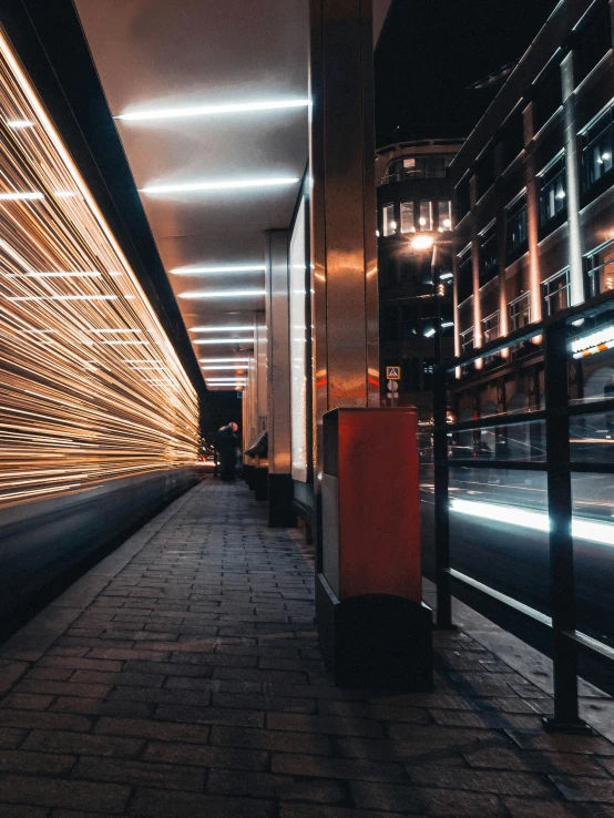 a train pulling into a train station at night, pexels contest winner, bus stop, modern street, profile picture, lines of lights