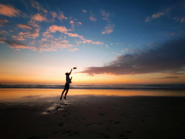 a person jumping into the air to catch a frisbee, by Jessie Algie, pexels contest winner, australian beach, predawn, instagram post, profile image