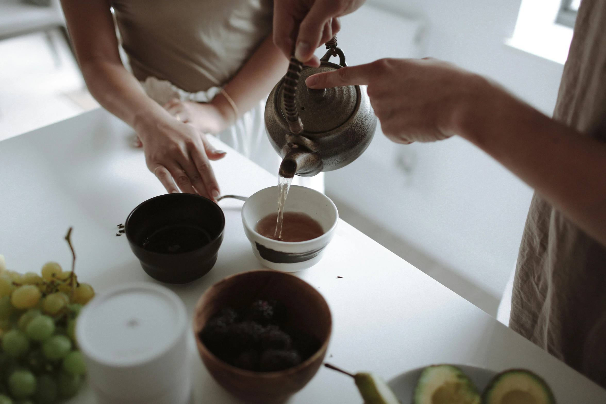 a woman pouring tea into a cup next to a bowl of fruit, by Emma Andijewska, trending on pexels, aussie baristas, avatar image, low quality grainy, cast