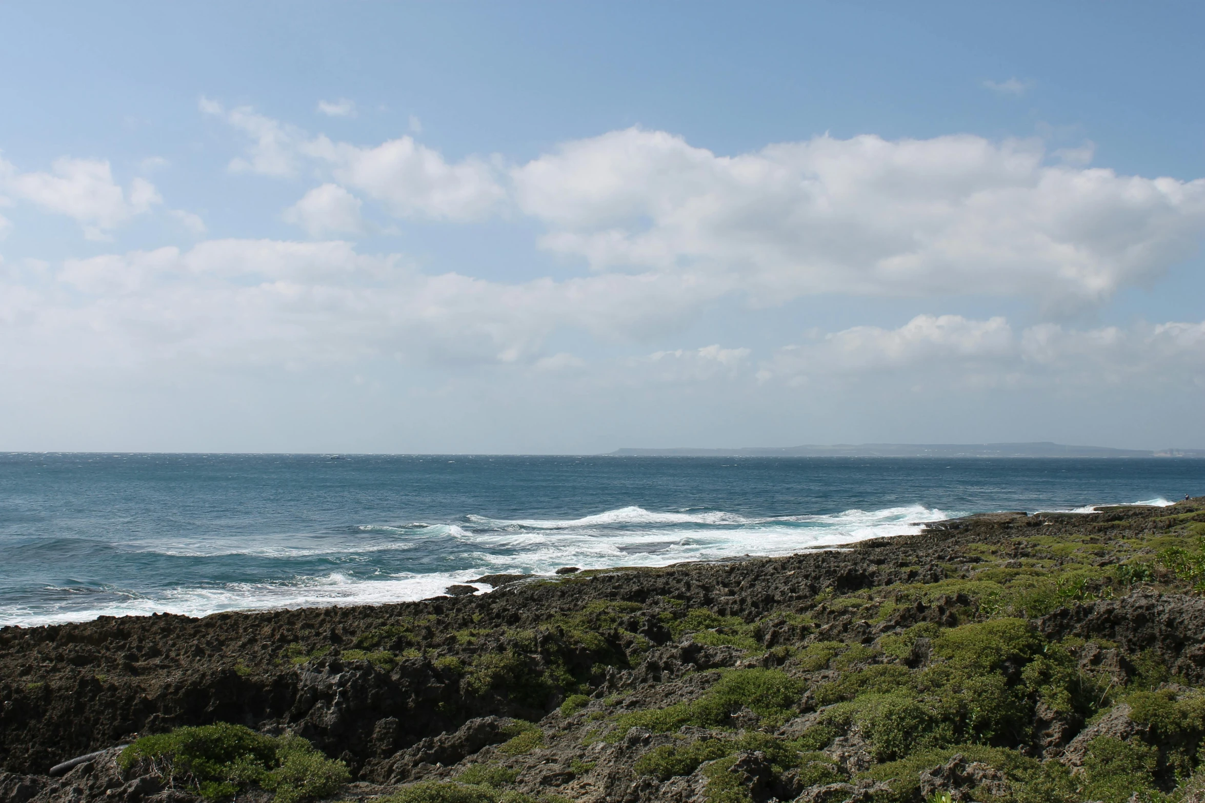 a large body of water near a grassy shore line