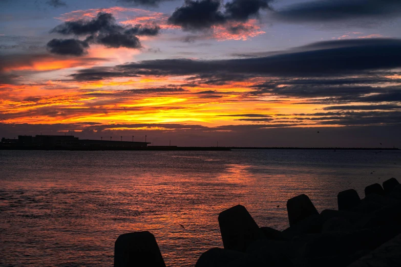 the setting sun lights up the horizon of a body of water