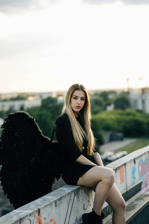 a beautiful young woman sitting on top of a bridge, by Julia Pishtar, pexels contest winner, renaissance, villainess has black angel wings, portrait of kim petras, ukraine. professional photo, standing on a rooftop