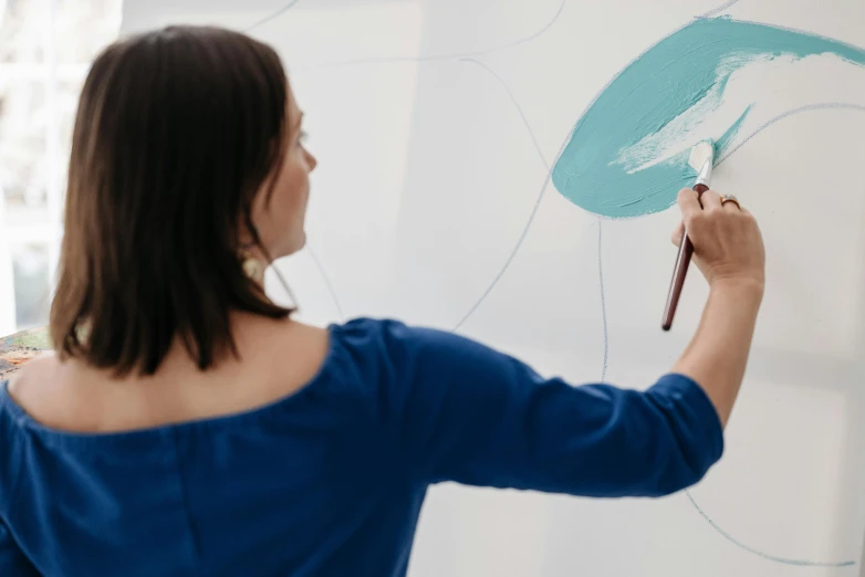 a woman is drawing on a white board, inspired by Hilma af Klint, trending on pexels, blue paint on top, round format, profile image, fan favorite