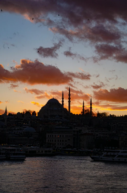 a large body of water under a cloudy sky, an album cover, inspired by Altoon Sultan, pexels contest winner, hurufiyya, vista of a city at sunset, black domes and spires, turkey, 2 5 6 x 2 5 6