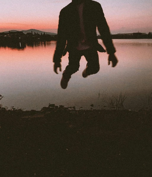 a person jumping in the air in front of a body of water, an album cover, pexels contest winner, spring evening, grainy low quality, creepy mood, [ floating ]!!