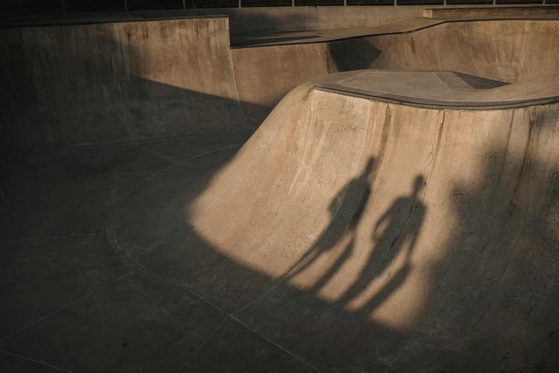 a man riding a skateboard up the side of a ramp, by Eglon van der Neer, pexels contest winner, concrete art, faces covered in shadows, two people, shot from a drone, rim lit