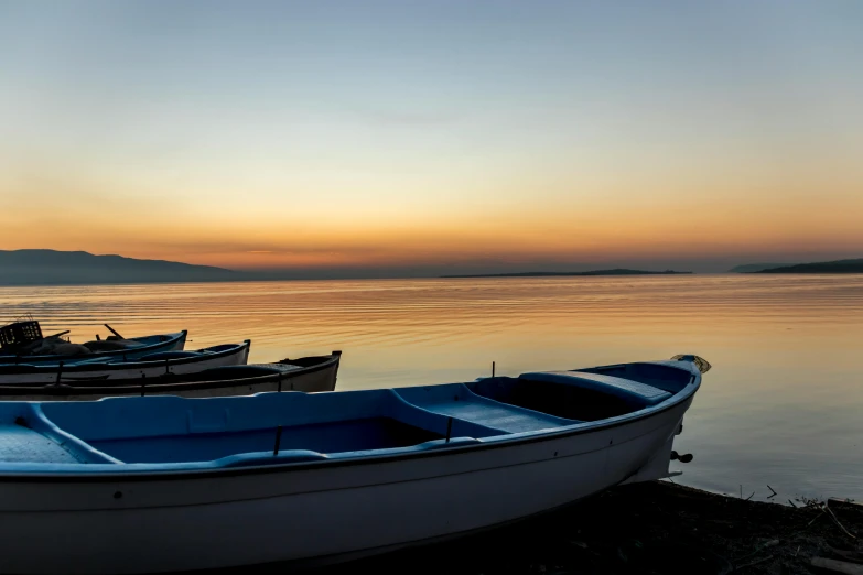 a couple of boats that are sitting in the water, pexels contest winner, romanticism, calm evening, lined up horizontally, shoreline, conor walton