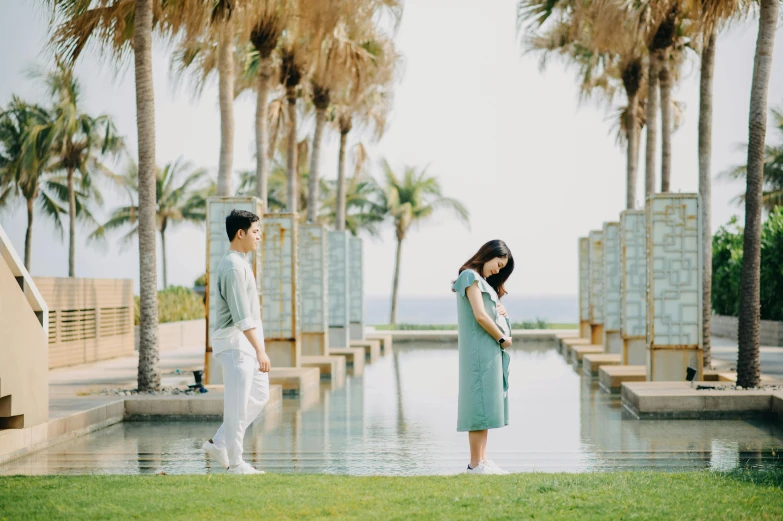 a couple of people standing on top of a lush green field, featuring marble fountains, standing beside the ocean, maternity feeling, xiang duan