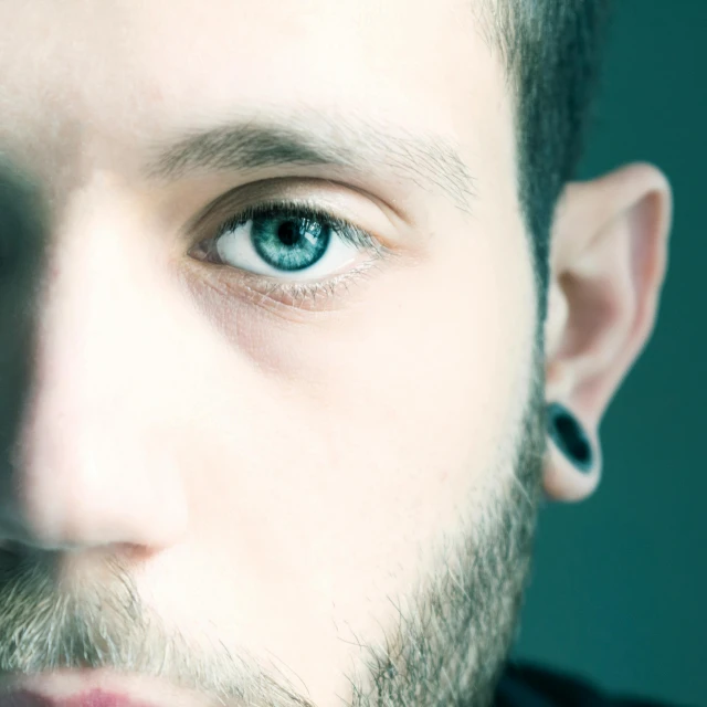 a close - up of a young man with short hair and big blue eyes