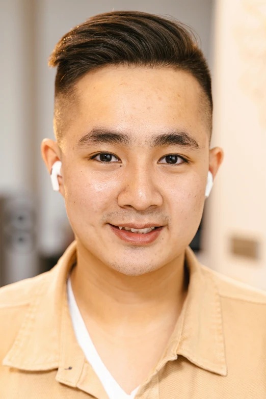 a man in a tan shirt posing for a picture, inspired by Tadashi Nakayama, trending on pexels, huge earrings and queer make up, south east asian with round face, earbuds, wearing professional makeup