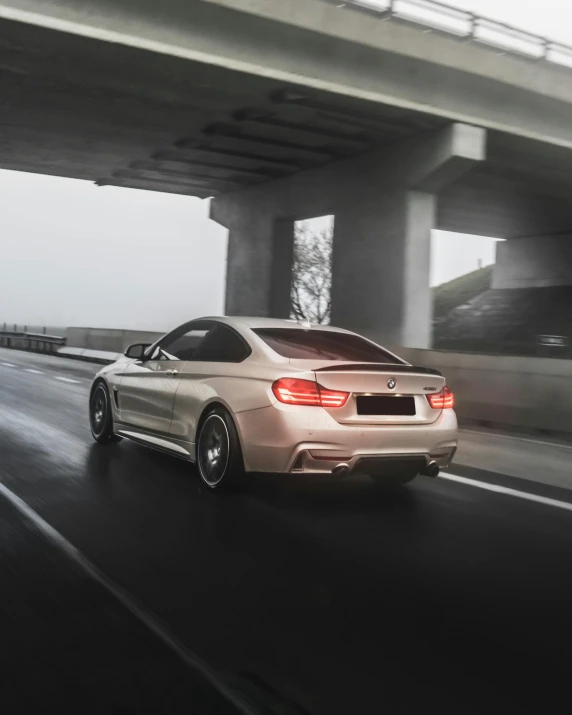 a car driving down a highway with a bridge in the background, by Adam Marczyński, pexels contest winner, pearlescent skin, bmw, back pose, desaturated