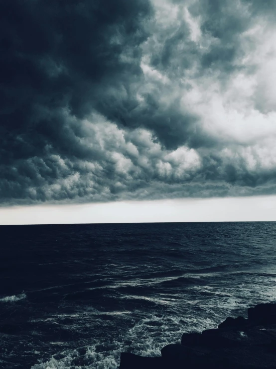 a black and white po of the ocean with an overcast sky