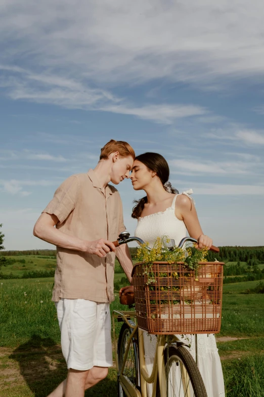 two people standing next to a bicycle, with the man kissing the woman