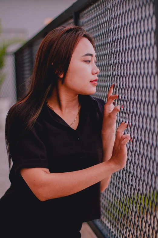 a woman leaning against a fence smoking a cigarette, inspired by Ruth Jên, trending on pexels, black shirt, asian female, chillhop, plain background