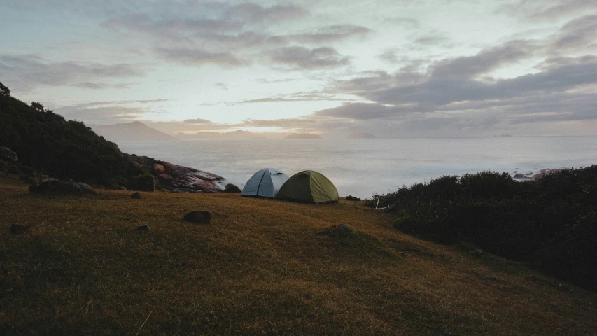 a couple of tents sitting on top of a hill, views to the ocean, lo-fi, ayne haag, dawn lighting