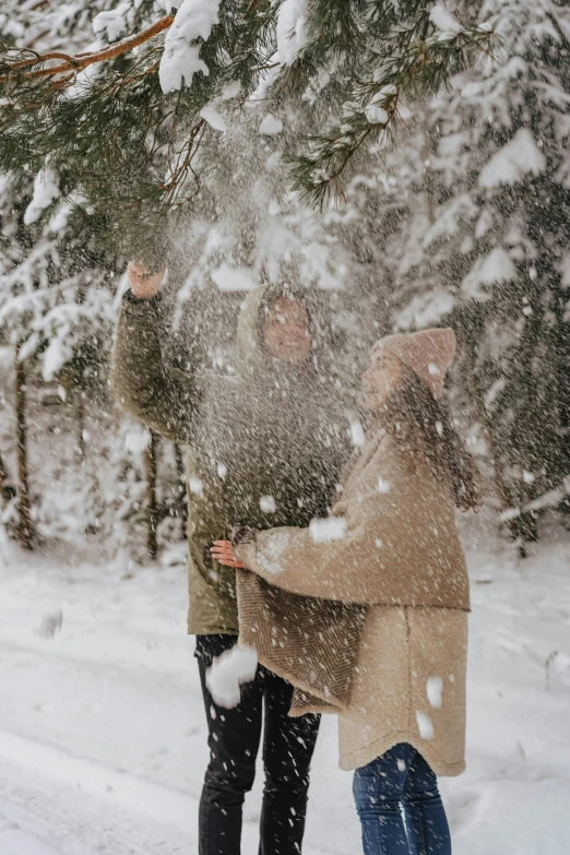 two people standing in the snow by trees