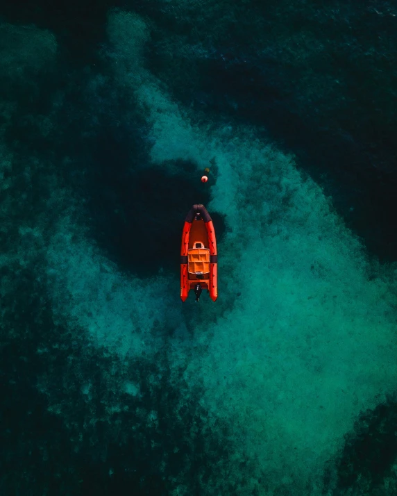 a boat in the middle of a body of water, looking down on the camera, red palette, clear blue water, unsplash photography