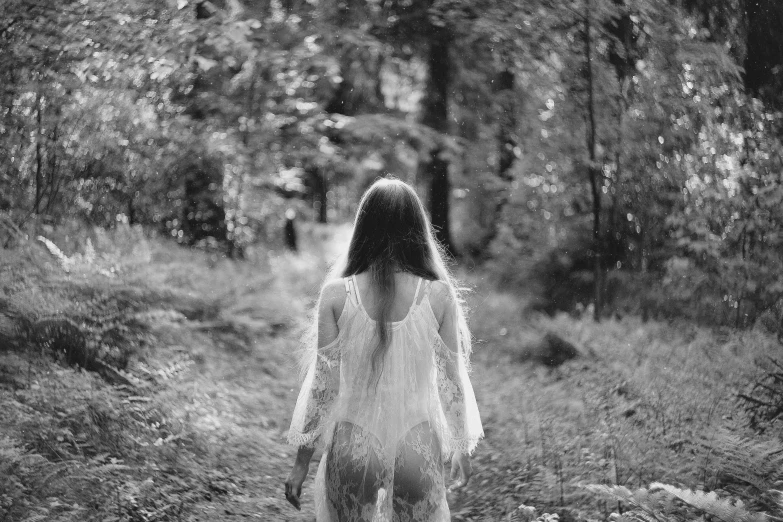 black and white pograph of a woman in a gown walking down a path