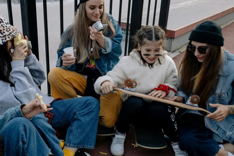 a group of young women sitting next to each other, a picture, by Emma Andijewska, trending on pexels, graffiti, skateboard, eating outside, young girl playing flute, flat lay