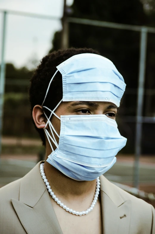 a man wearing a face mask on a tennis court, an album cover, pexels, surgical supplies, looking from side, covered in bandages, african american