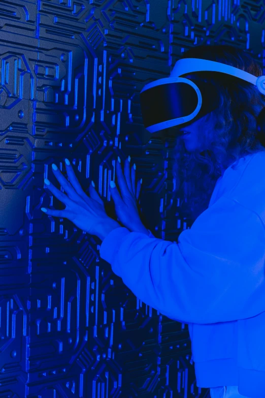 a woman is wearing a virtual reality headset, interactive art, glowing blue interior components, covered in circuitry, with a blue background, reaching