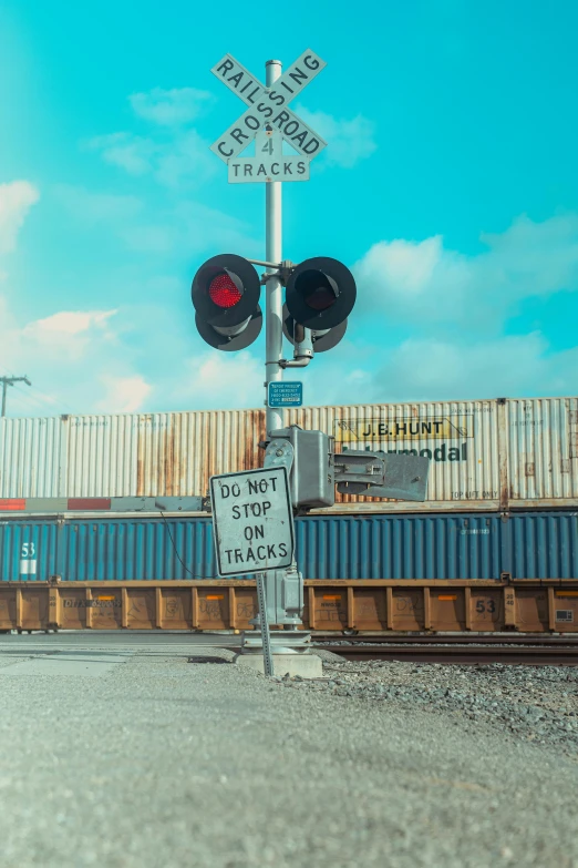 a railroad crossing sign sitting on the side of a road, an album cover, unsplash, shipping containers, 🚿🗝📝