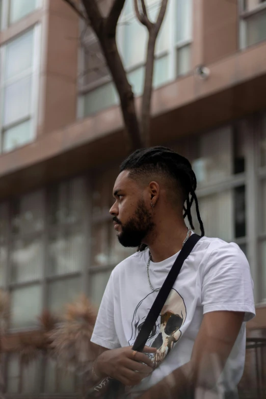 a man with dreadlocks sitting on a bench, inspired by Paul Georges, pexels contest winner, profile image, man in white t - shirt, standing in a city street, spiky black hair and dark skin