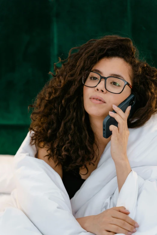 a woman laying in bed talking on a cell phone, trending on pexels, renaissance, wavy long black hair and glasses, tech robes, curly brown hair, customers