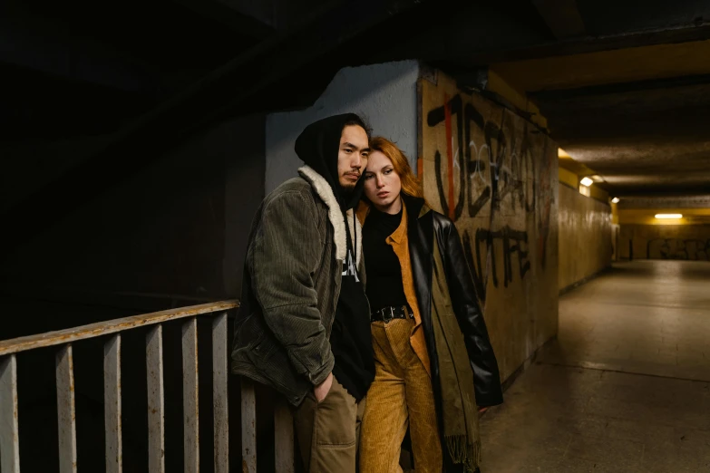 a man and a woman standing next to each other, a portrait, inspired by Nan Goldin, unsplash, graffiti, ellie bamber, cinematic outfit photo, tunnels, cinematic luts