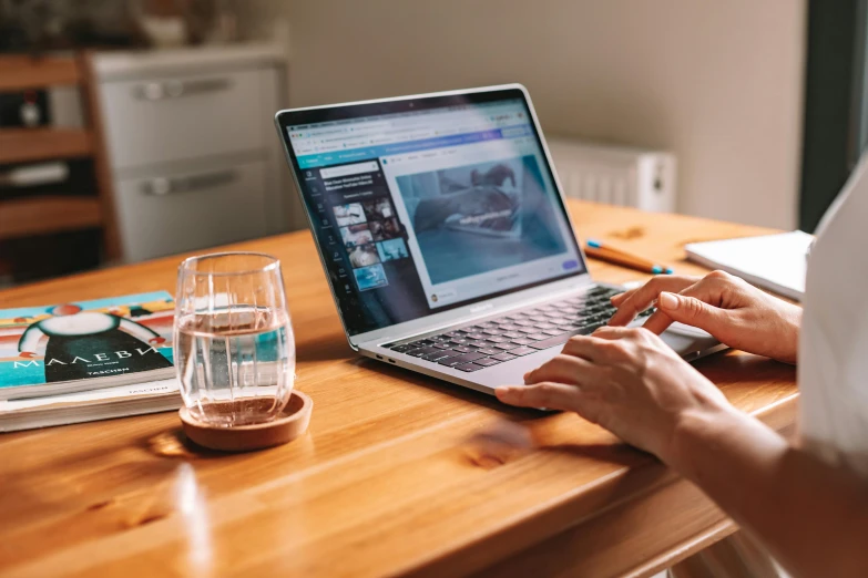 a person using a laptop on a wooden table, trending on pexels, filling with water, lawther sit at table playing dnd, avatar image