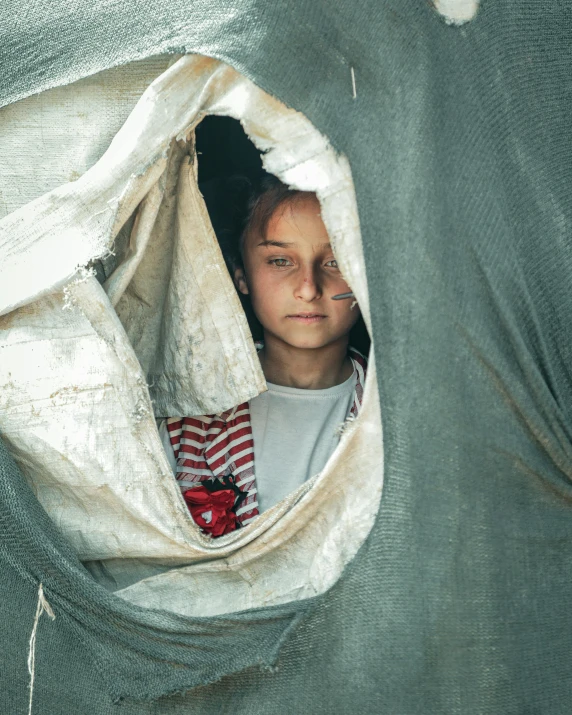 a young girl peeks out of a hole in an elephant's trunk, by Elsa Bleda, unsplash contest winner, hurufiyya, tents, refugees, made of fabric, wide eyed