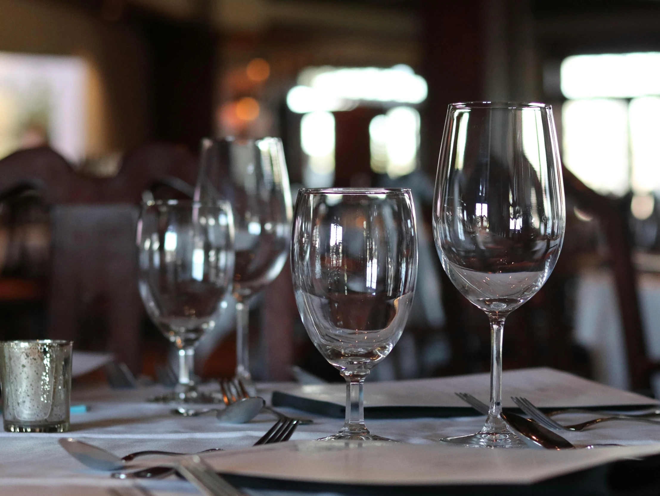 a couple of wine glasses sitting on top of a table, long table, up close