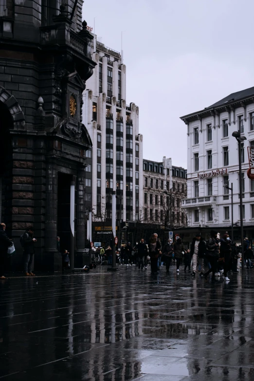 a group of people walking in the rain past tall buildings
