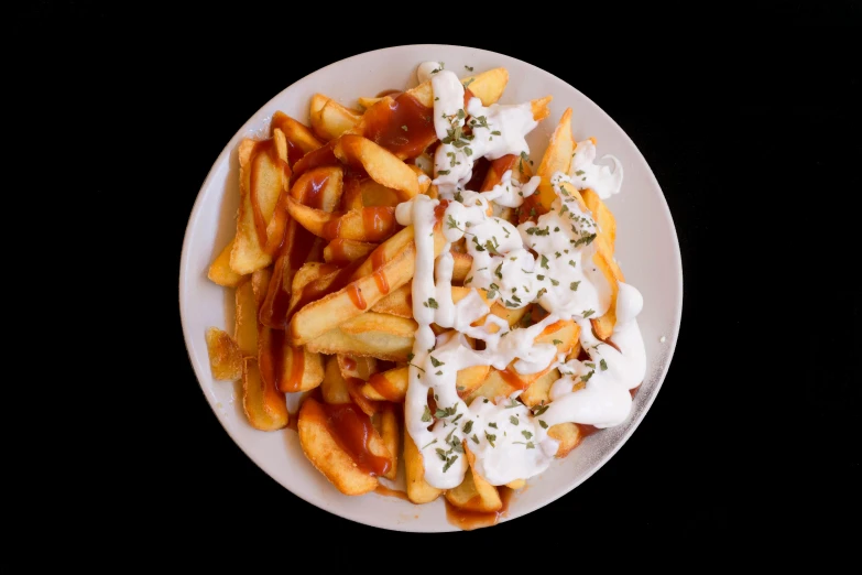 a plate of french fries with sour cream, ketchup and mayonnaise