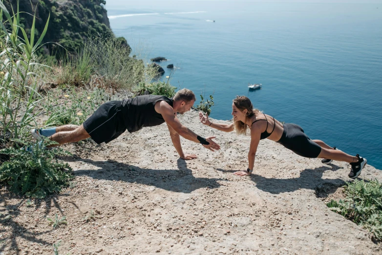 two women performing a handstand while standing on a cliff next to the ocean