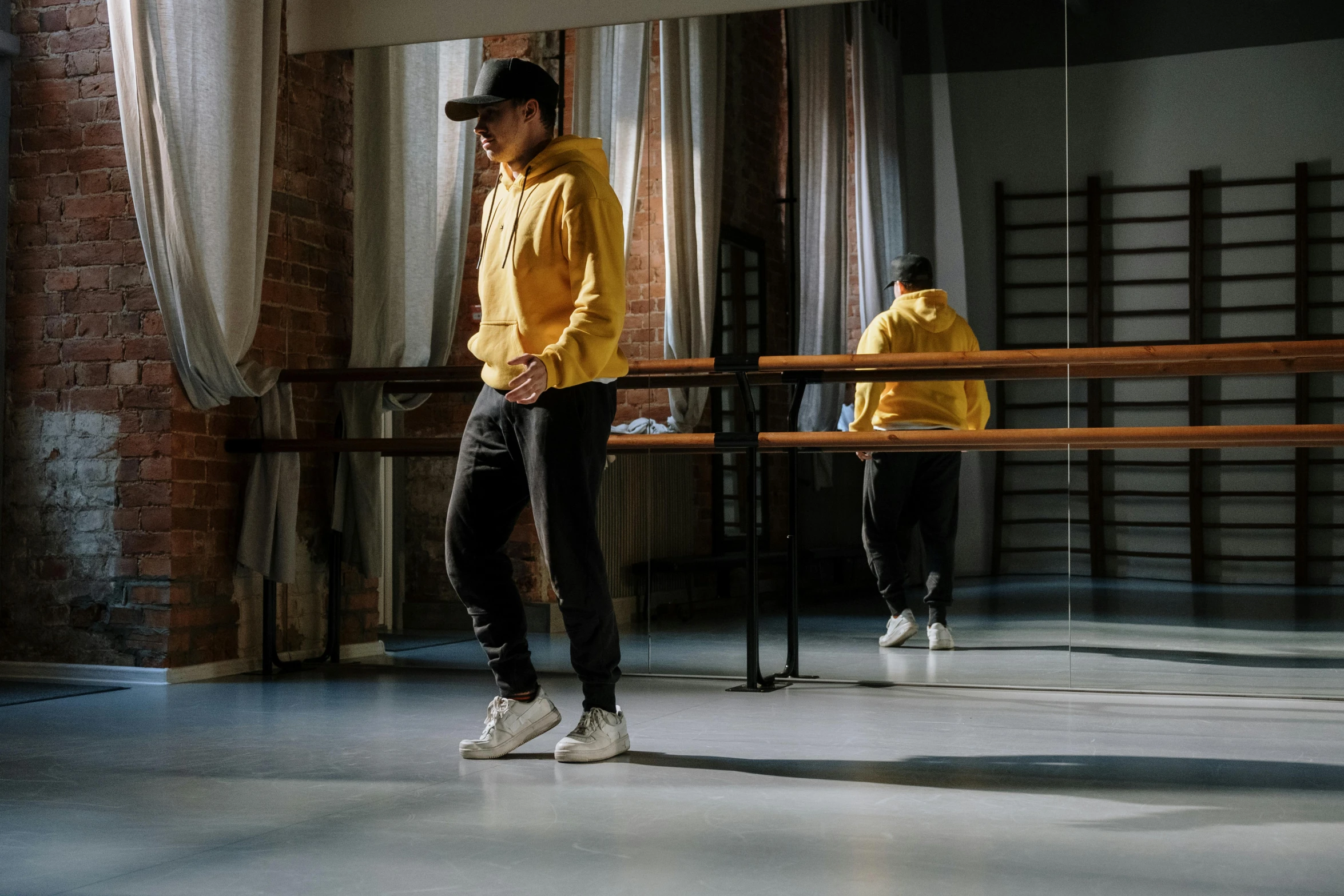 a man in a yellow shirt is standing in a dance studio, inspired by Fei Danxu, trending on unsplash, hyperrealism, hat and hoodie, sitting on a table, cinematic outfit photo, thumbnail