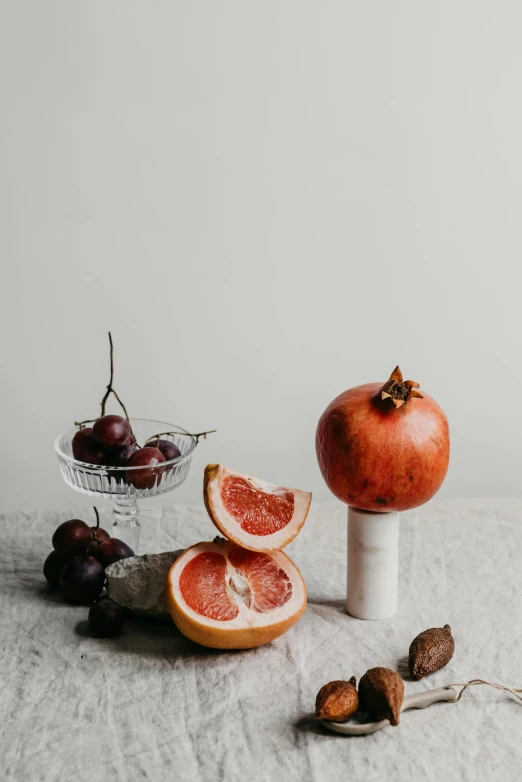 a bunch of grapefruits sitting on top of a table, a still life, by Rebecca Horn, trending on pexels, on a marble pedestal, obsidian pomegranade, minimalistic composition, maroon and white