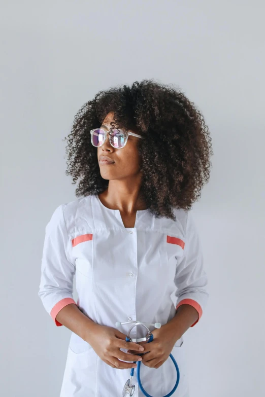 a woman in a lab coat holding a stethoscope, pexels contest winner, afrofuturism, long afro hair, square rimmed glasses, white waist apron and undershirt, color block