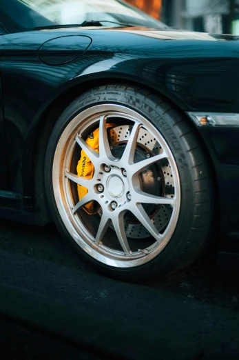 a black sports car parked on the side of the road, pexels contest winner, hyperrealism, detailed alloy wheels, silver and yellow color scheme, professional closeup photo, taken in the late 2000s
