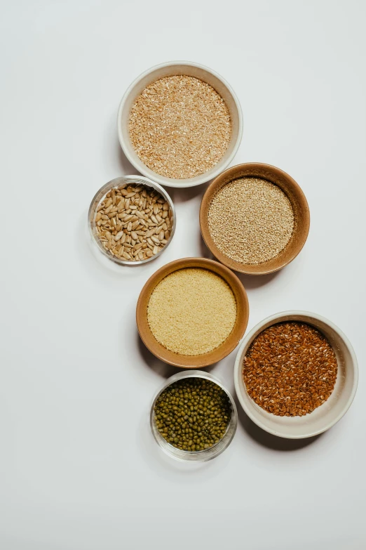 a group of bowls filled with different types of cereal, pexels, renaissance, sand particles, detailed product image, greens), high quality product image”