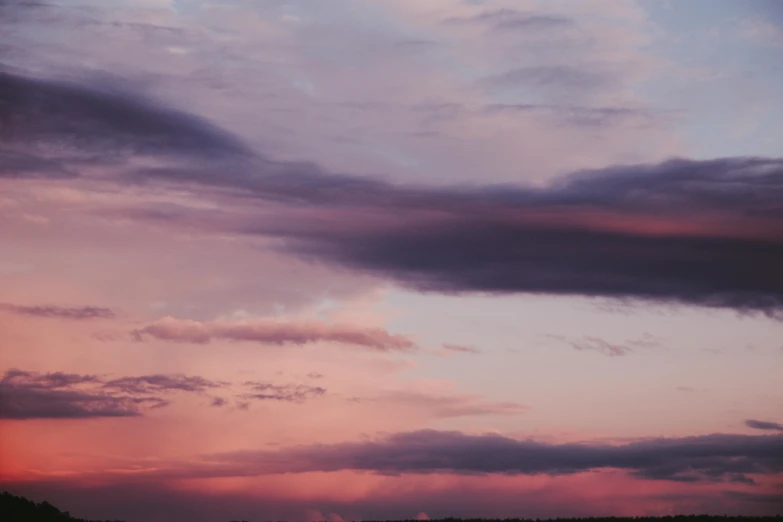 a plane in the sky at sunset on a cloudy day