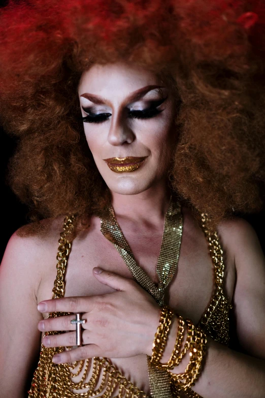 a woman wearing gold and black makeup looks like a drag queen
