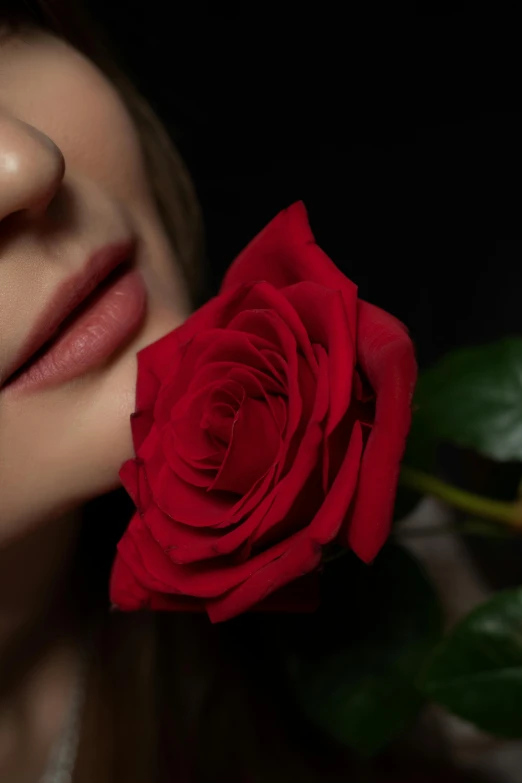 a woman holding a red rose up to her face