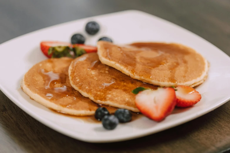 a white plate topped with pancakes and strawberries, unsplash, blueberries on the side, caramel, local foods, background image