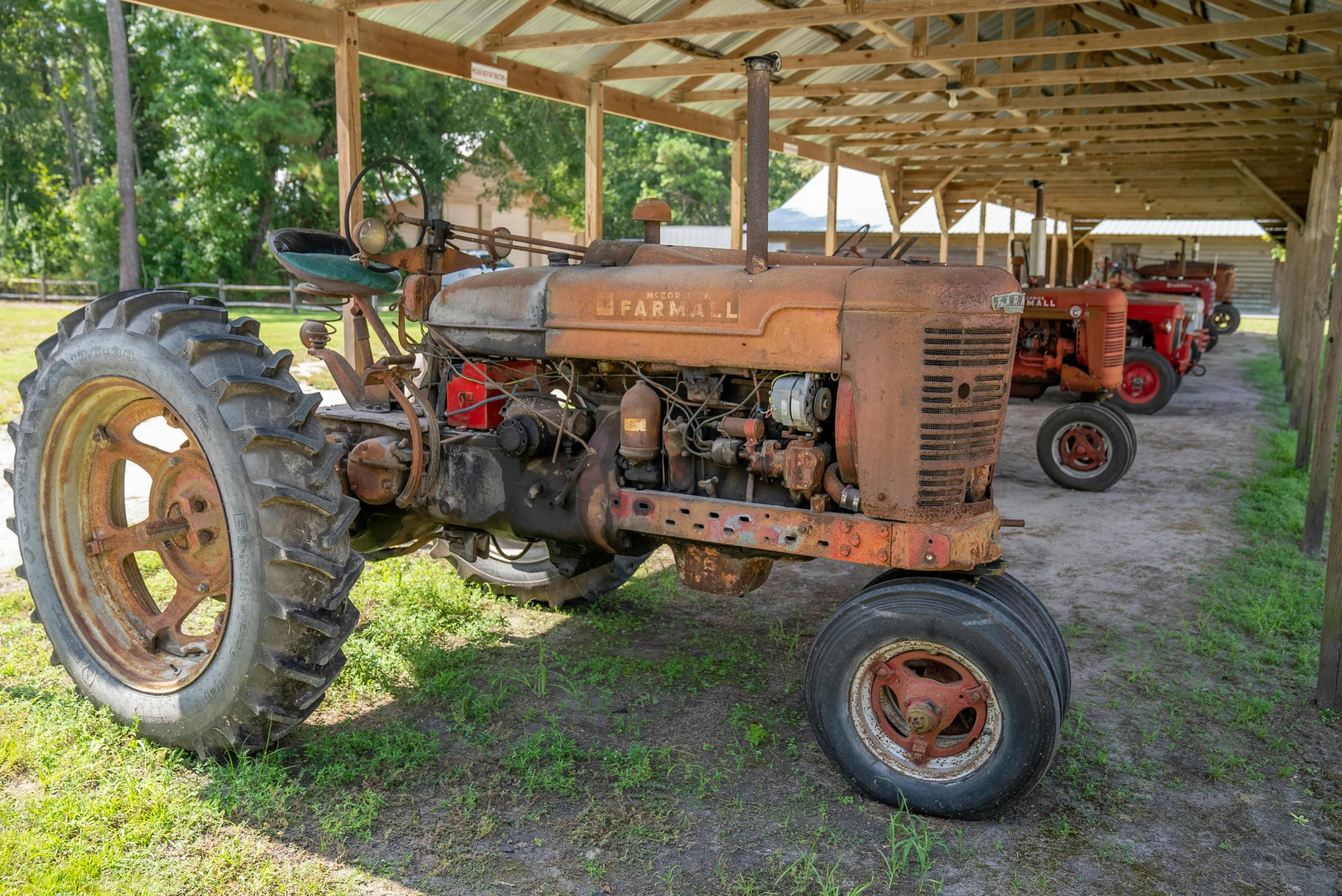 an old tractor is parked under a covered structure, a portrait, by Arnie Swekel, pixabay, florida, in a row, a photograph of a rusty, 🦩🪐🐞👩🏻🦳