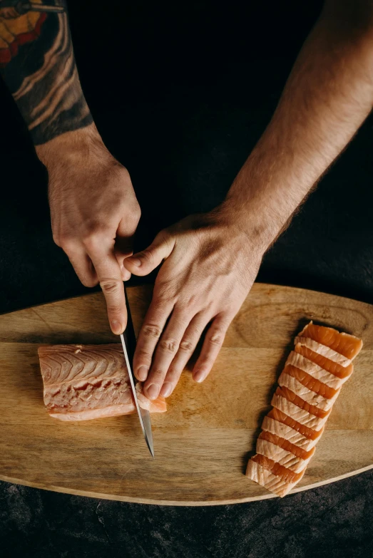 a person cutting a piece of salmon on a cutting board, a tattoo, by Daniel Seghers, four hands, vertical orientation, connectivity, handcrafted